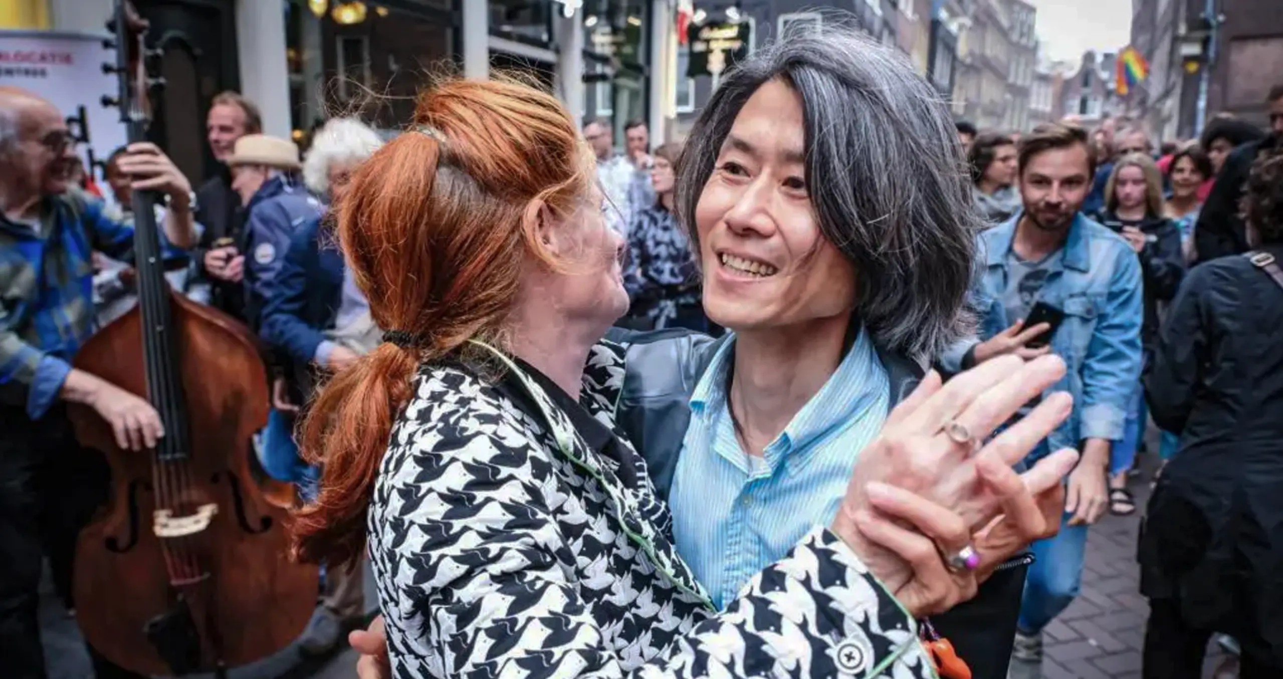 Mensen dansen op de straat tijdens het Red Light Jazz Festival, met muzikanten op de achtergrond