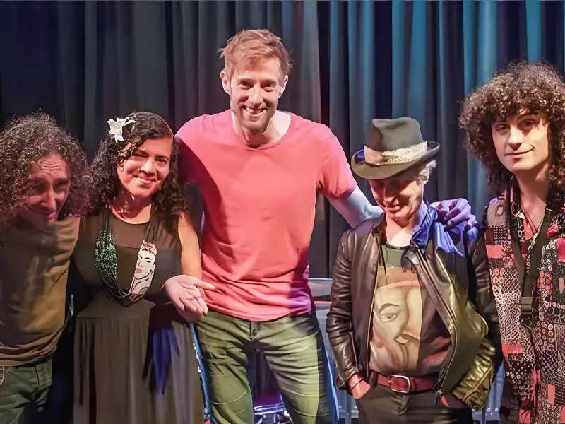 Vijf bandleden van Achha staan samen op het podium en poseren na een optreden.