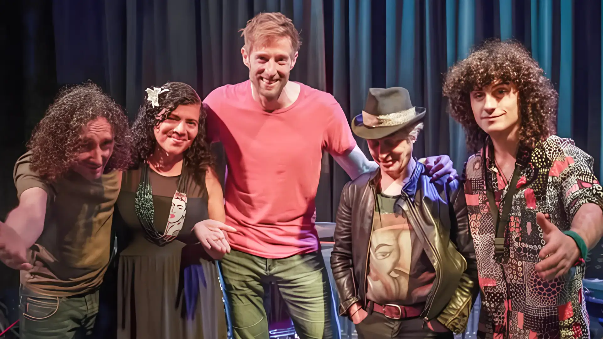 Vijf bandleden van Achha staan samen op het podium en poseren na een optreden.