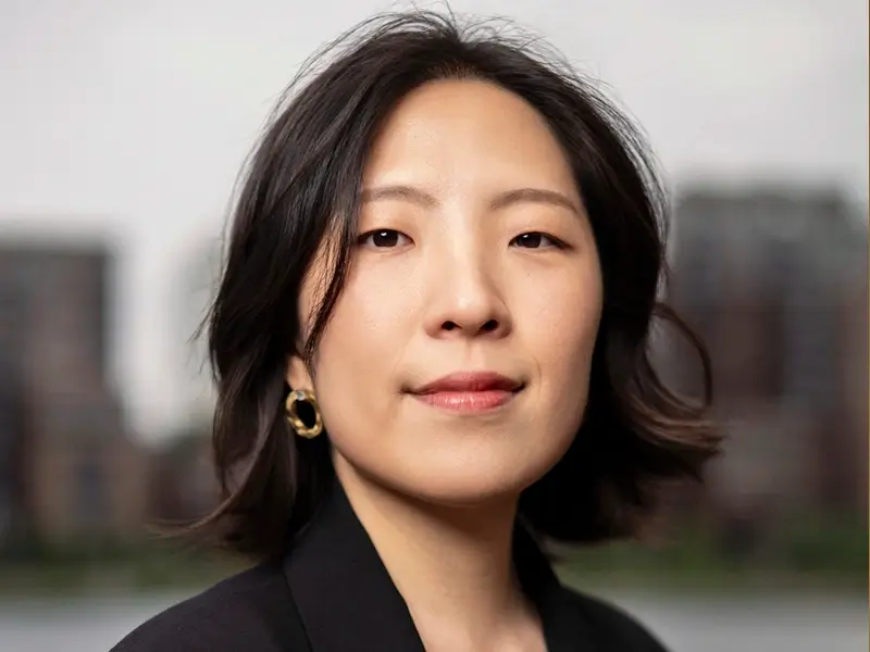 Zwart-wit portret van jazzpianiste Miran Noh, frontaal kijkend, met een rustige en zelfverzekerde uitstraling tegen een zacht vervaagde stedelijke achtergrond.