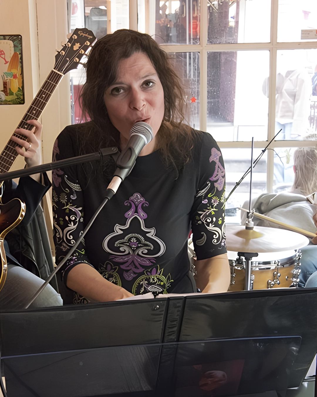 Ruth Geerse zingt en speelt piano tijdens een live optreden in een intieme setting, begeleid door een gitarist en drummer.