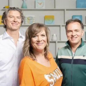 Drie muzikanten van Something About Sanna poseren samen en kijken glimlachend in de camera.