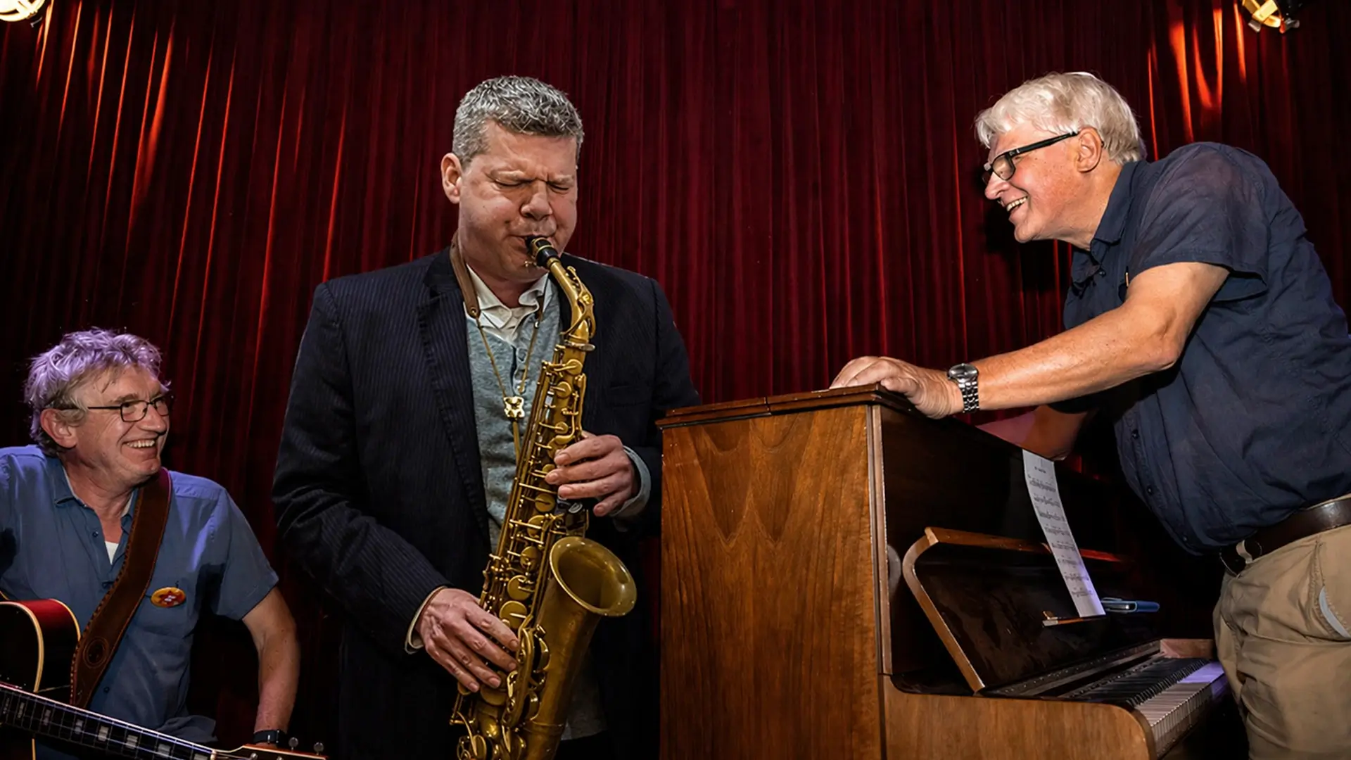 Jazz musicians Berend van den Berg (piano), Joep Lumeij (guitar/double bass) and Marco Kegel (saxophone) performing together in an intimate setting during Red Light Jazz Festival.