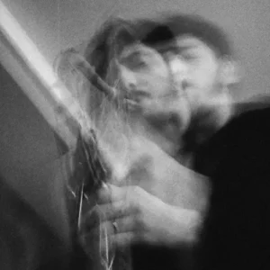 A saxophonist plays in an artistic black-and-white image with a blurred, double-exposure effect emphasizing movement and expression.