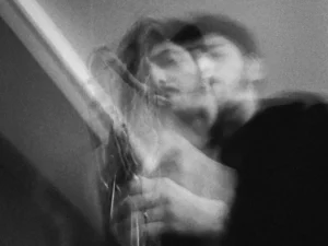 A saxophonist plays in an artistic black-and-white image with a blurred, double-exposure effect emphasizing movement and expression.