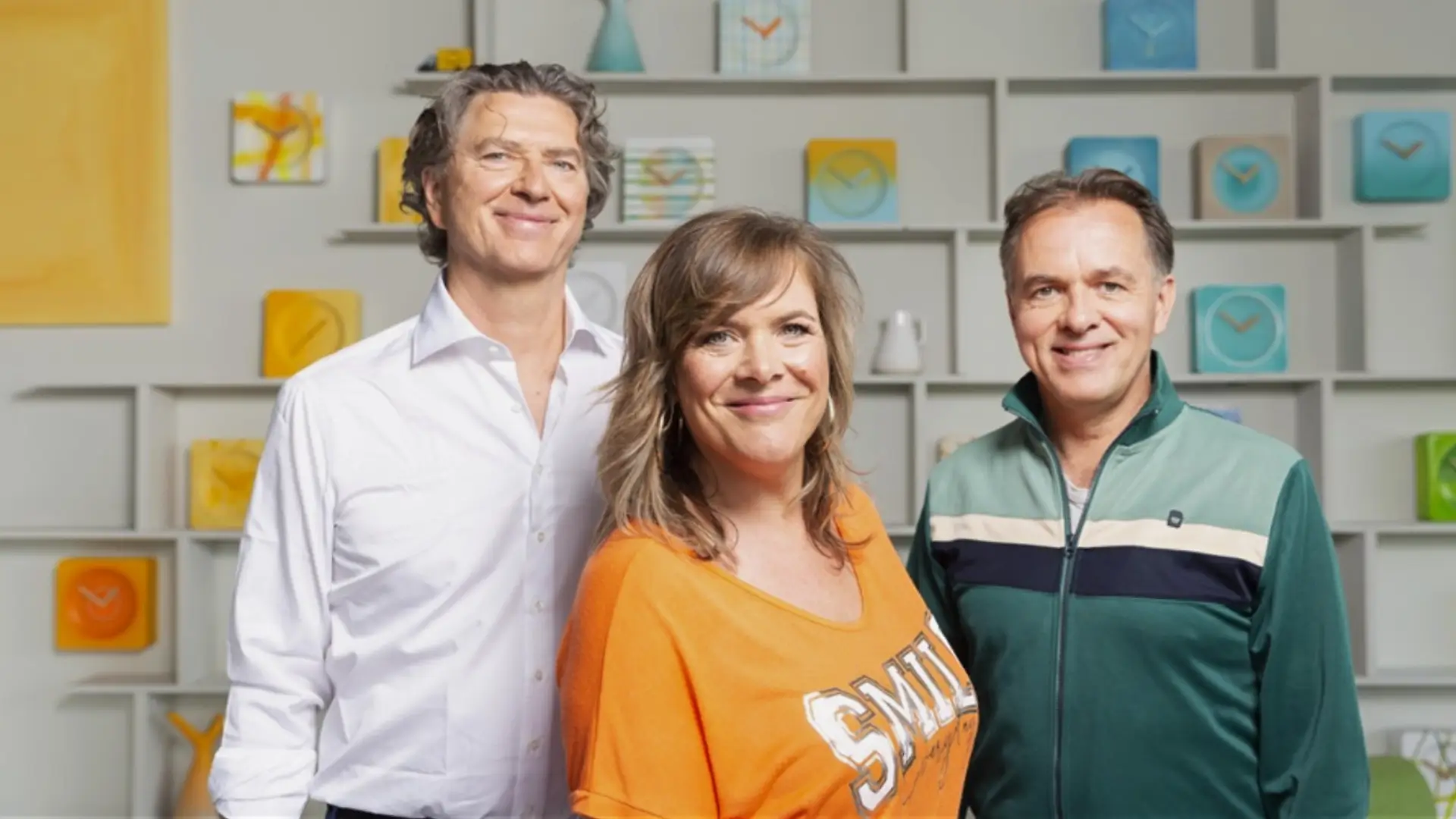 Drie muzikanten van Something About Sanna poseren samen en kijken glimlachend in de camera.