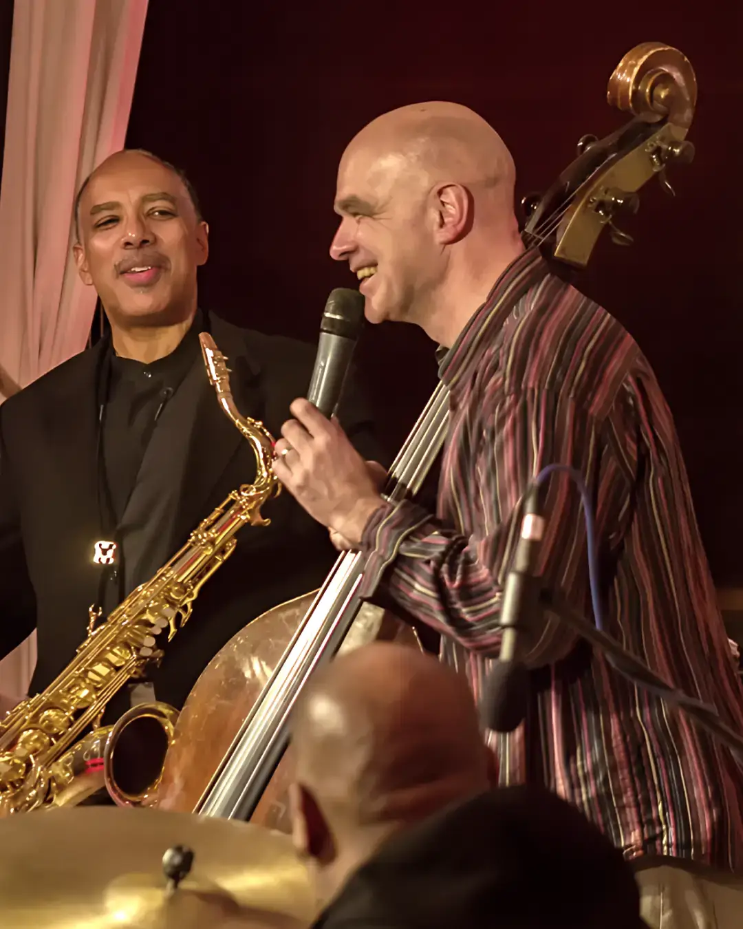 Saxofonist en bassist van Trio of Liberty staan samen op het podium en maken contact tijdens een live optreden.