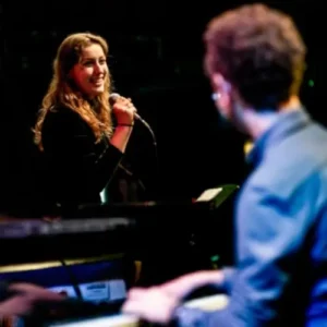 Anna Sollewijn zingt terwijl Chris Müller piano speelt tijdens een live optreden.