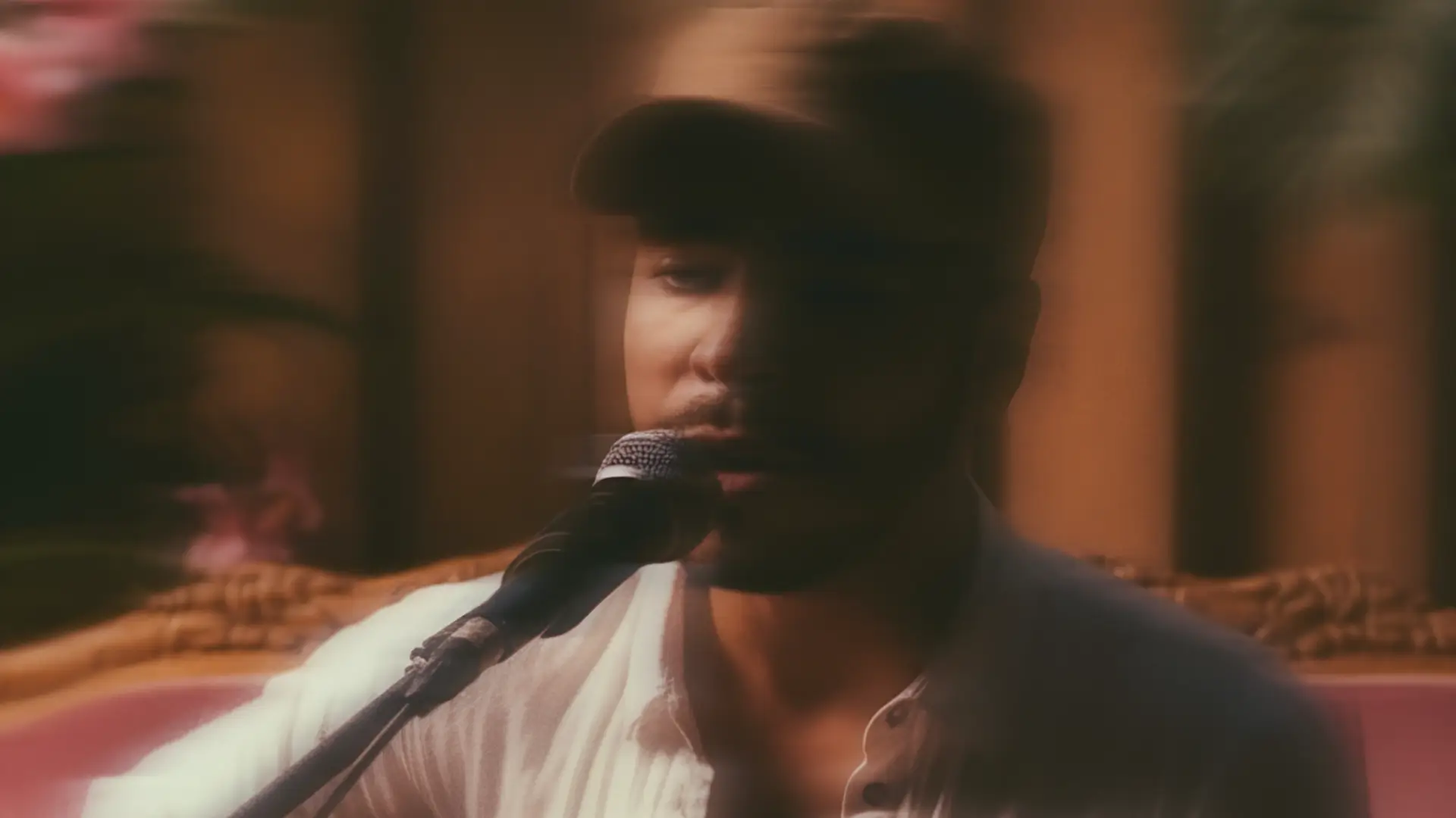 Zanger en gitarist Fernando Oliveira zingt in een warme, sfeervolle setting in de microfoon tijdens een intieme live performance.